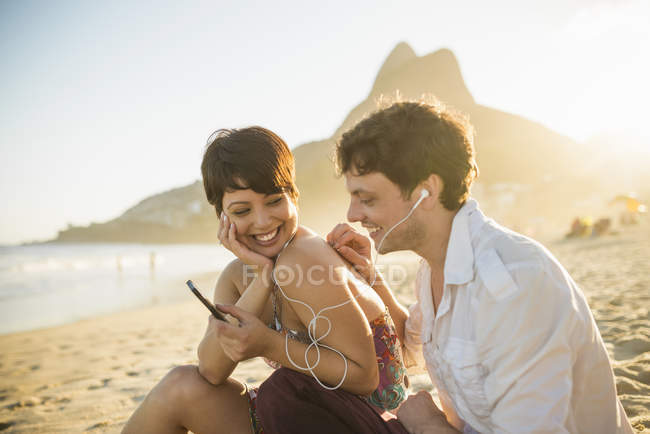 Junges paar hört musik, strand von ipanema, rio, brasilien — Stockfoto