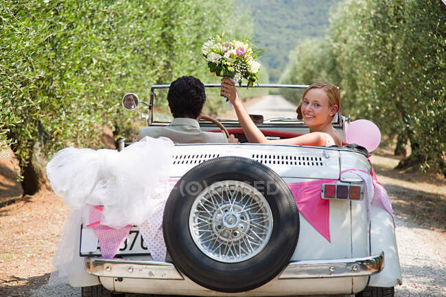 Recién casados en coche clásico - foto de stock