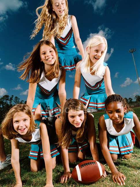 Cheerleaders kneeling on top of each other, portrait — Stock Photo