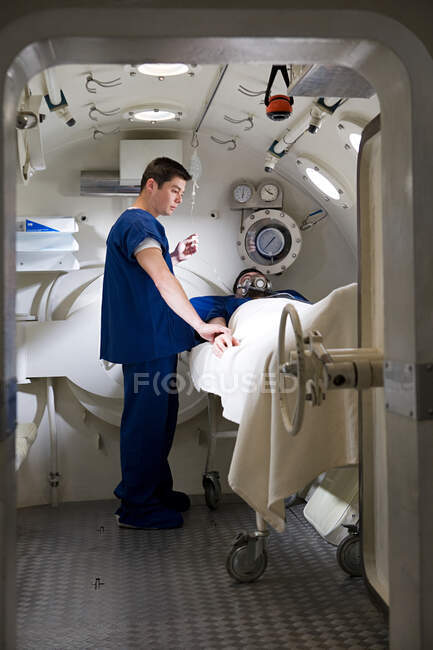 Enfermera llevando paciente a cámara hiperbárica - foto de stock