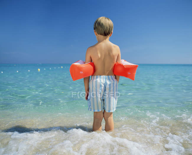 Rear view of boy paddling with armbands — Stock Photo