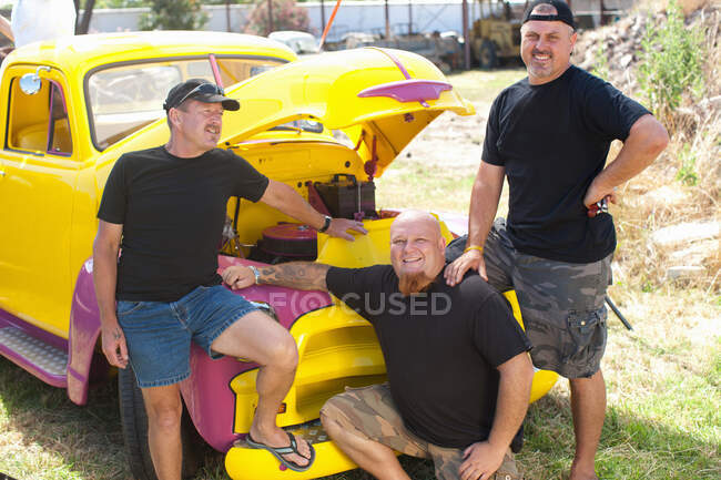 Hombres sonriendo con coche colorido - foto de stock