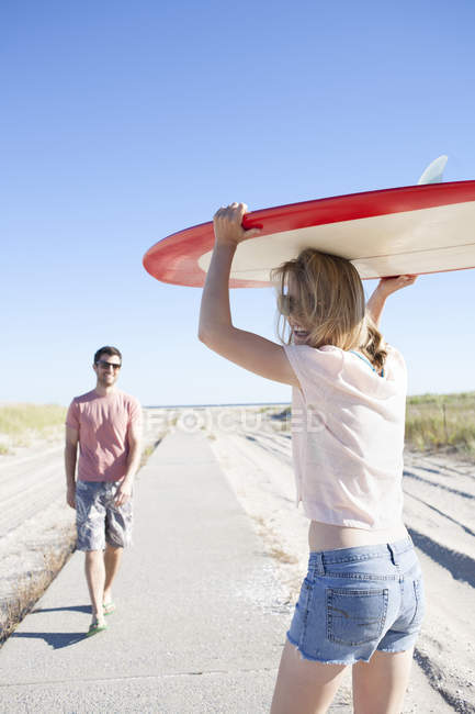 Casal carregando prancha de surf no caminho costeiro, Breezy Point, Queens, Nova York, EUA — Fotografia de Stock