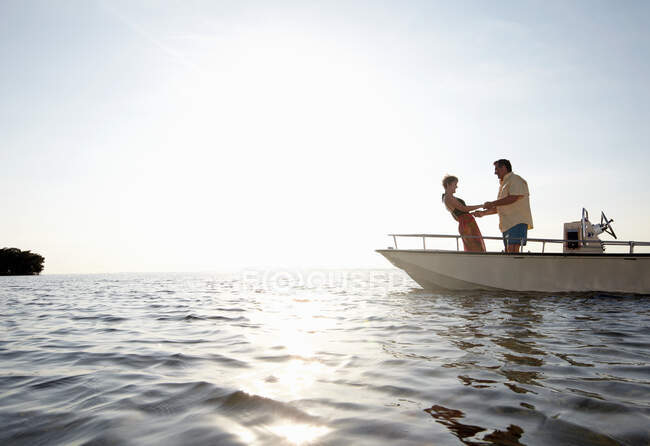 Старша пара тримає руки на моторному човні — стокове фото