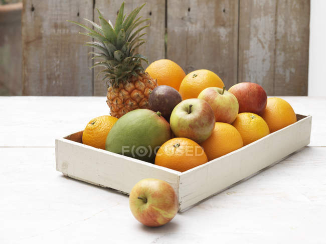 Selección de fruta en caja sobre mesa de madera blanqueada - foto de stock