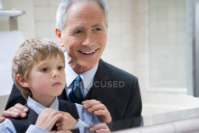Hombre ayudando a nieto a atar su corbata - foto de stock