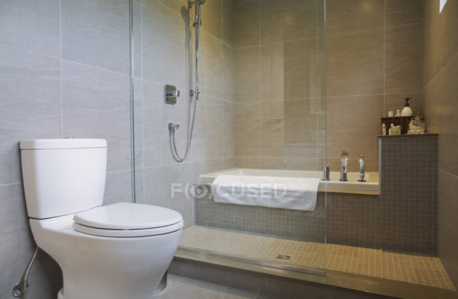 Современный санузел с ванной, туалетом и стеклянным душем — стоковое фото