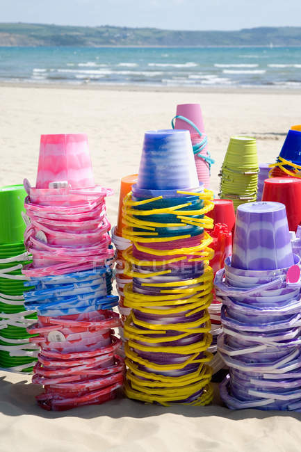 Stacks of buckets on sandy beach in sunlight — Stock Photo