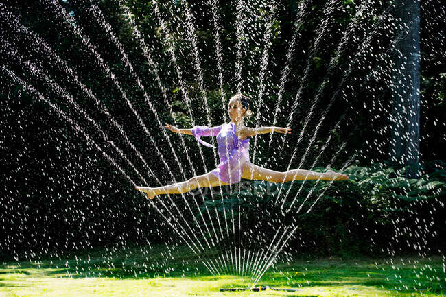 Bailarina saltando através de um aspersor de água — Fotografia de Stock