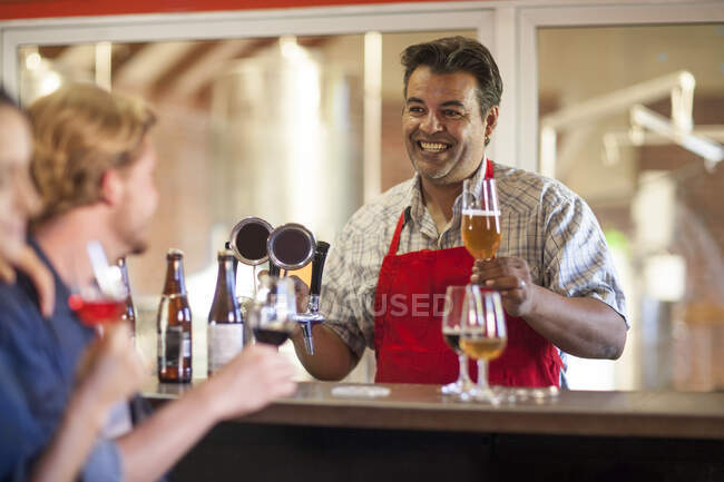 Ciudad del Cabo, Sudáfrica, camarero de edad avanzada que ofrece su vaso de cerveza en el bar de la cervecería - foto de stock