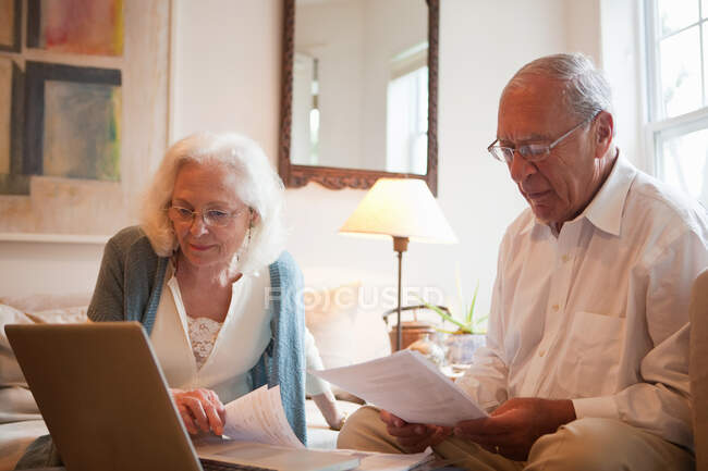 Старшая пара с ноутбуком в доме — стоковое фото