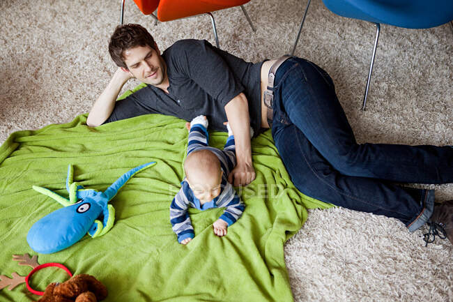 Father playing with baby son in living room — Stock Photo