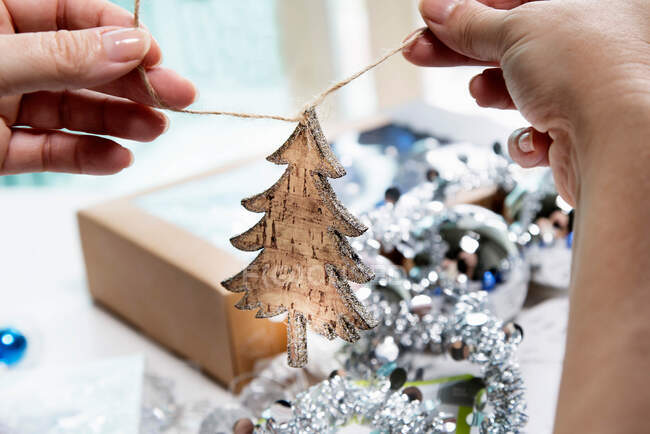Person's hands preparing wooden christmas tree shaped christmas decoration — Stock Photo