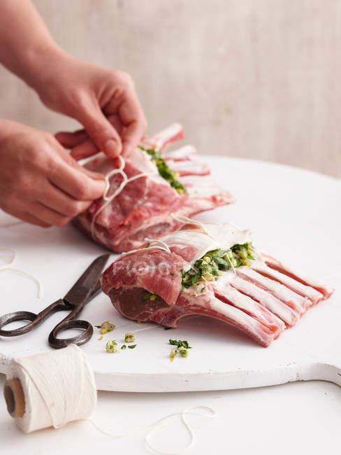 Close-up view of person hands tying stuffed lamb racks — Stock Photo