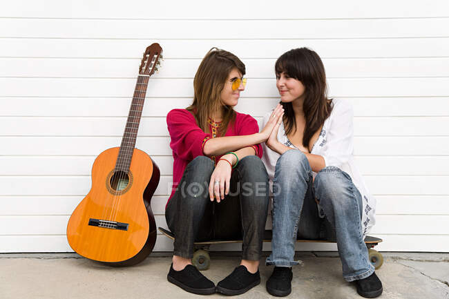 Две девушки сидят на полу с гитарой — стоковое фото