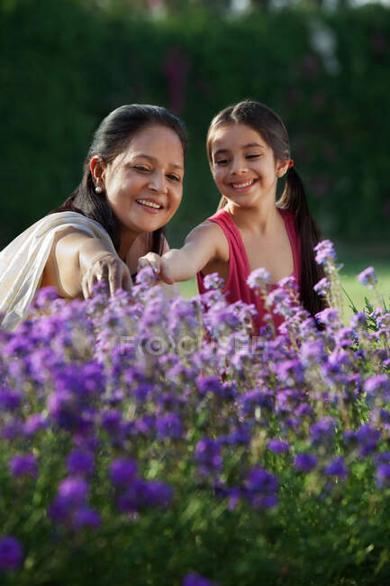 Girl and her grandmother looking at flowers — Stock Photo