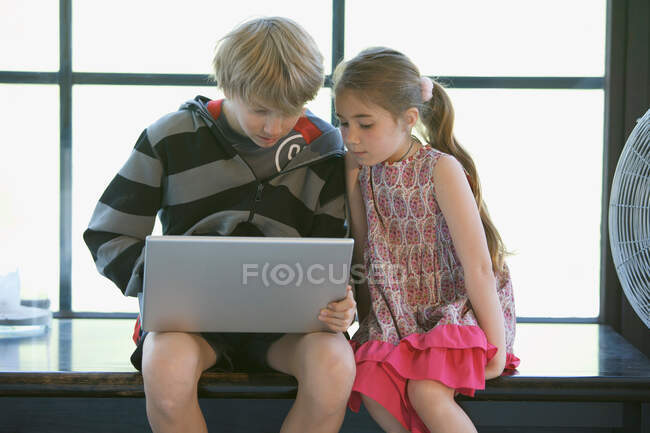 Menina e menino no computador em casa — Fotografia de Stock