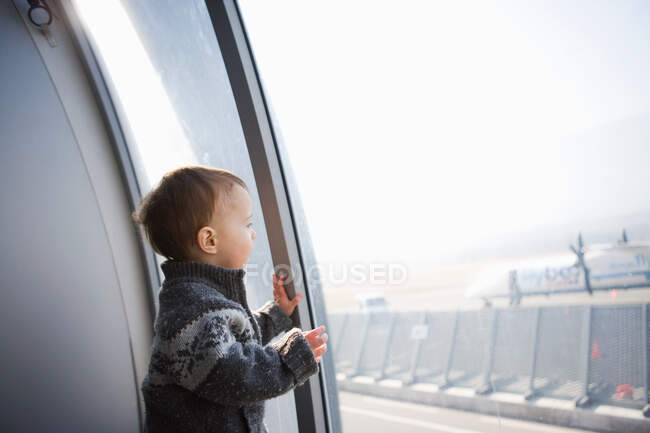 Chico mirando por la ventana del aeropuerto - foto de stock