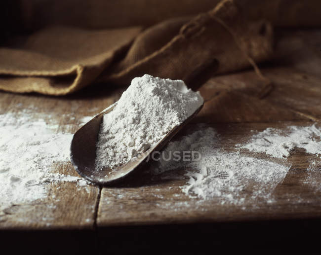 Colher de farinha branca na mesa de madeira — Fotografia de Stock
