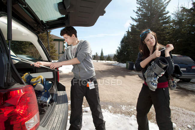 Два молодых взрослых человека упаковывают багажник с лыжным снаряжением — стоковое фото
