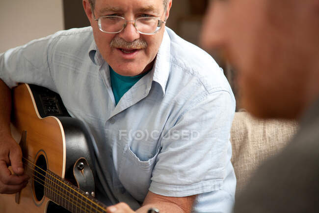 Зрелый человек играет на гитаре — стоковое фото