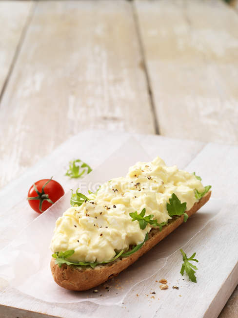 Mayonnaise aux œufs au poivre moulu sur baguette croustillante aux feuilles de salade et tomate cerise — Photo de stock