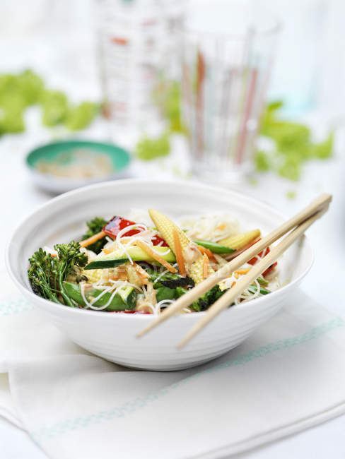 Bowl of vegetables and noodles on garden table — Stock Photo