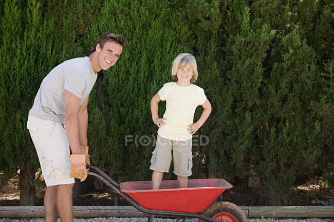 Father pushing son in wheelbarrow — Stock Photo