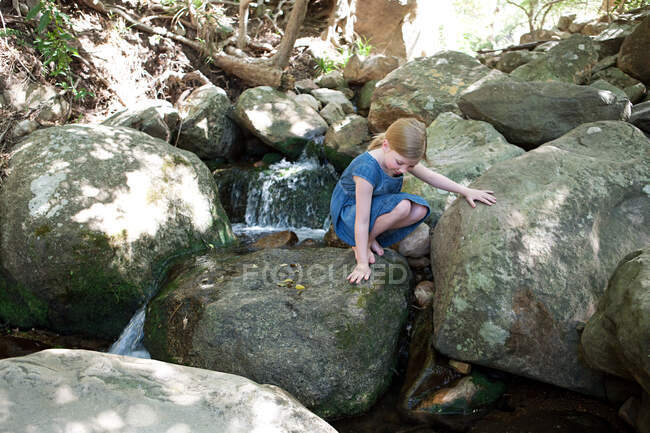 Menina em rochas por rio — Fotografia de Stock