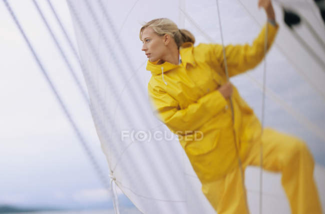 Woman on boat in yellow waterproofs, holding rope — Stock Photo