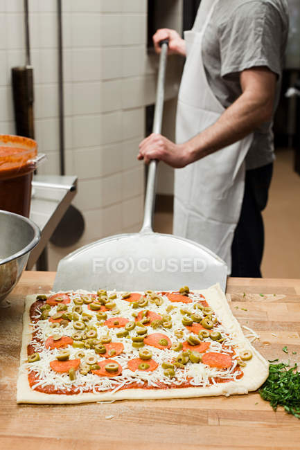 Мужчина-повар делает пиццу на коммерческой кухне — стоковое фото