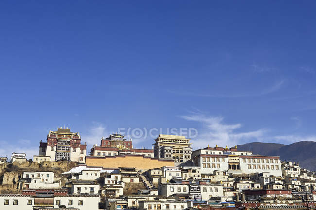 Edificios del monasterio de Ganden Sumtseling contra el cielo azul, Condado de Shangri-la, Yunnan, China - foto de stock