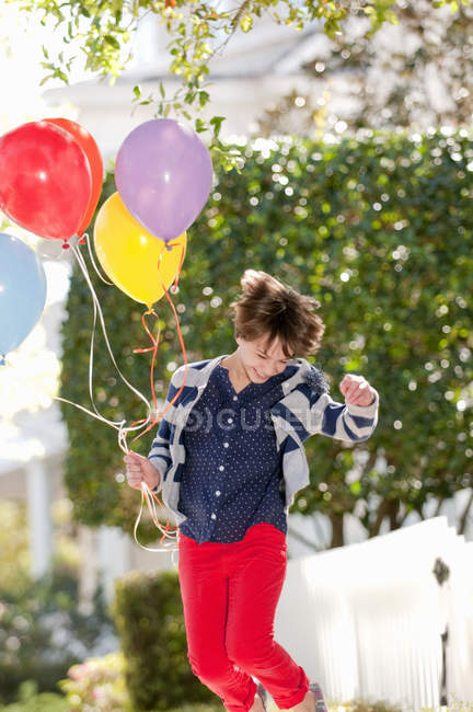 Десятирічна дівчинка схвильовано стрибає з купою кульок — стокове фото