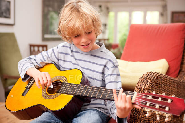 Молодий хлопчик грає на гітарі вдома — стокове фото