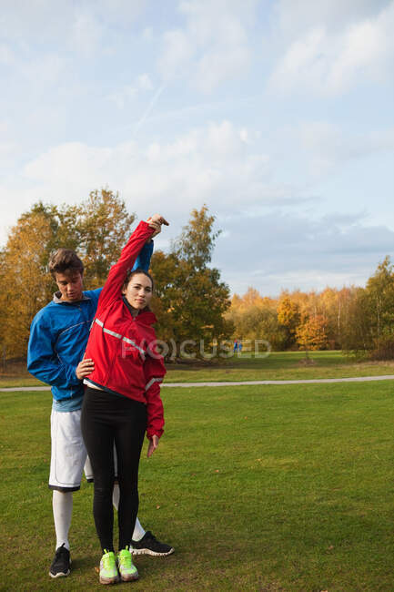 Personal trainer assisting young woman with warm up exercises — Stock Photo