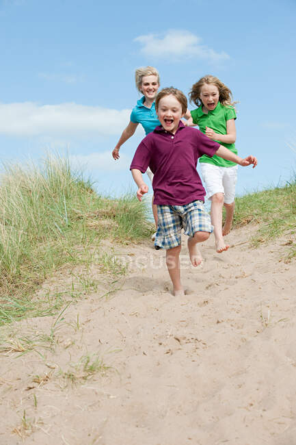 Irmão e irmãs correndo para a praia — Fotografia de Stock