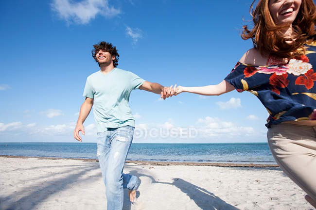 Giovane coppia che si tiene per mano sulla spiaggia — Foto stock