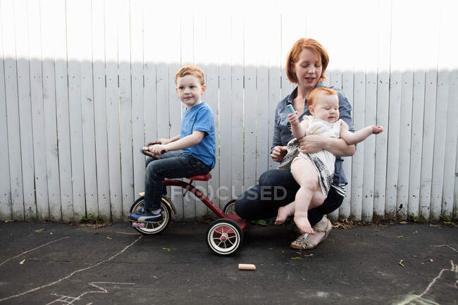 Madre jugando en el patio con dos niños - foto de stock