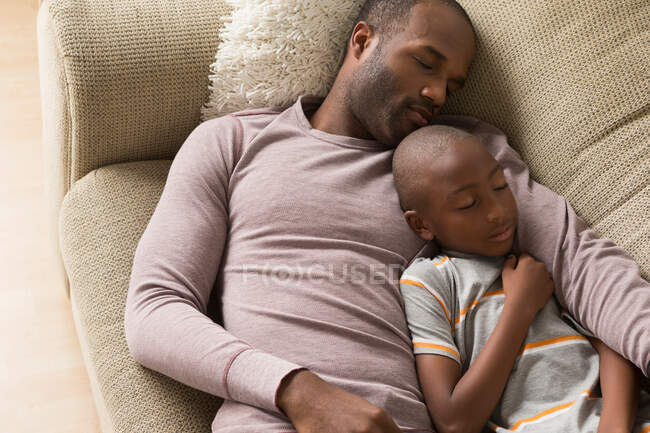 Отец и сын спят на диване — стоковое фото