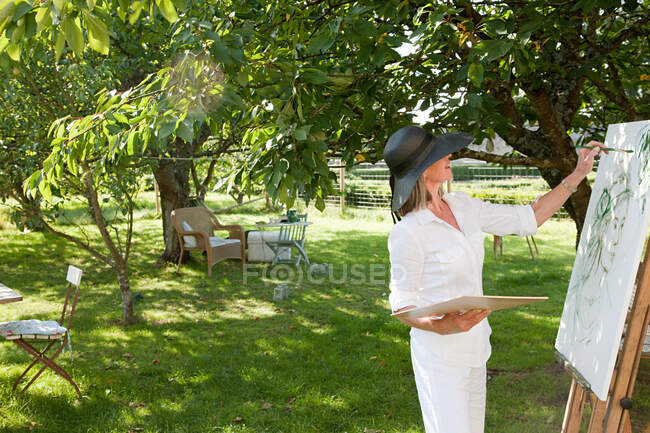 Mature woman painting at easel — Stock Photo