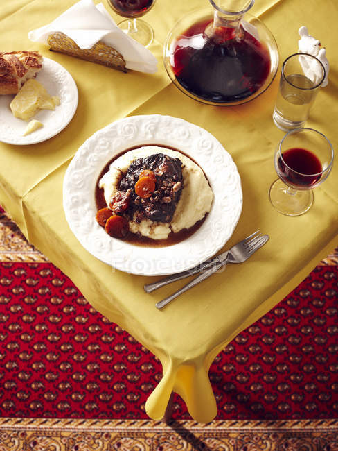 Vista dall'alto del tavolo con stufato di guanciale di manzo e caraffa di vino rosso — Foto stock