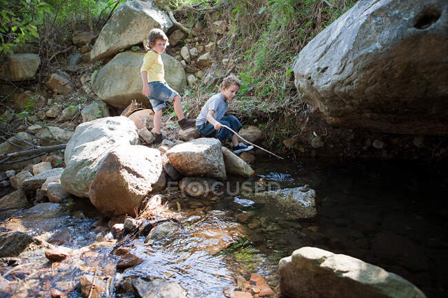 Chicos en las rocas por el río - foto de stock