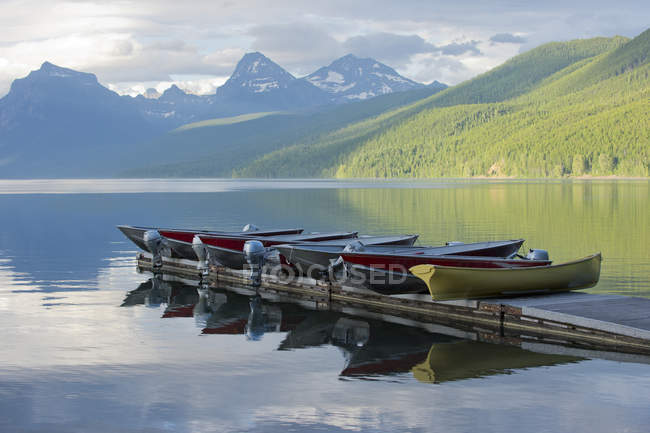 Muelle con embarcaciones amarradas y paisaje de montaña - foto de stock