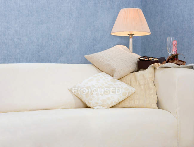 Sofa with champagne and chocolates — Stock Photo