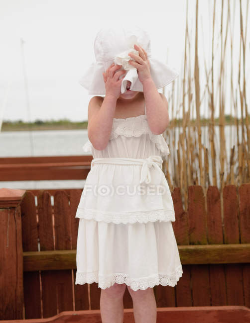 Menina cobrindo rosto com chapéu de sol branco — Fotografia de Stock