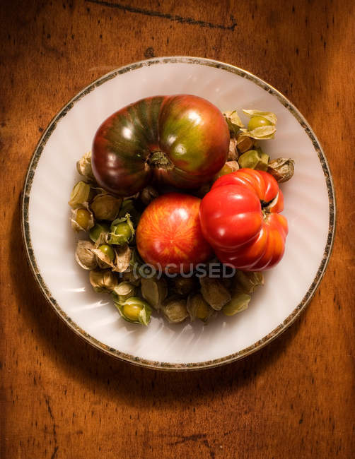 Heirloom tomatoes and tomatillos on plate, top view — Stock Photo