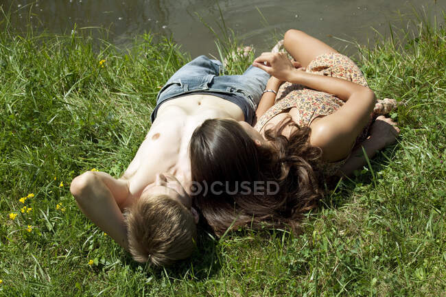 Jeune couple reposant au bord de la rivière — Photo de stock