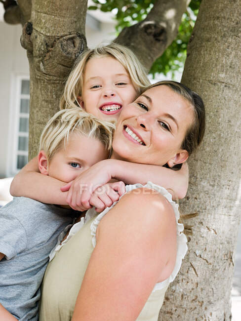 Madre con hijo e hija por árbol - foto de stock