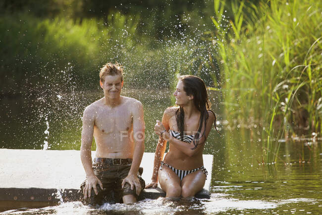 Adolescente menina salpicando namorado no rio — Fotografia de Stock