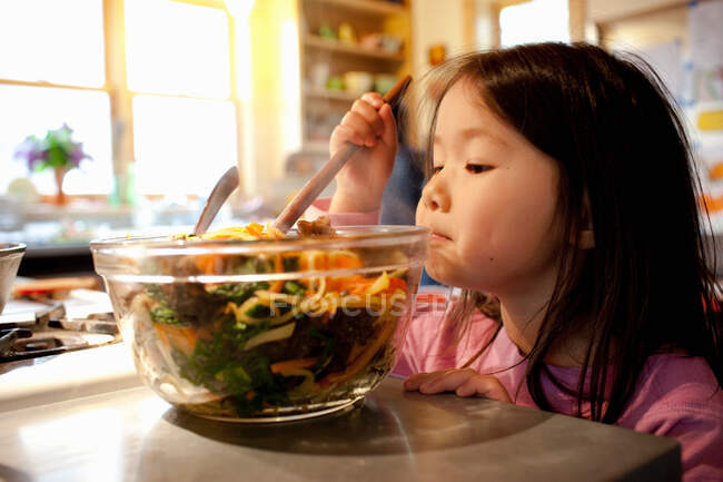 Chica mezcla ensalada en ensaladera - foto de stock